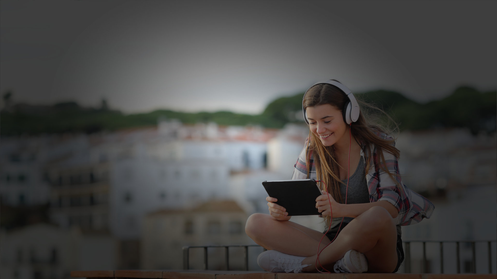 Nastolatka ze słuchawkami na uszach ogląda tv na tablecie
